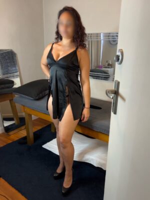 Sensual masseuse Monique standing next to massage table with a glory hole